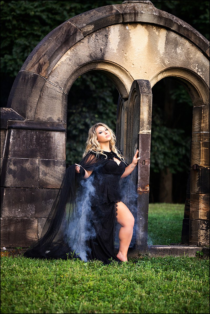 Halloween boudoir photo shoot outside in cemetery with woman in black lack dress with feather cape and fog coming from behind, fun photo shoots pittsburgh Halloween boudoir photo shoot outside in cemetery with woman in black lack dress with feather cape and fog coming from behind, fun photo shoots pittsburgh