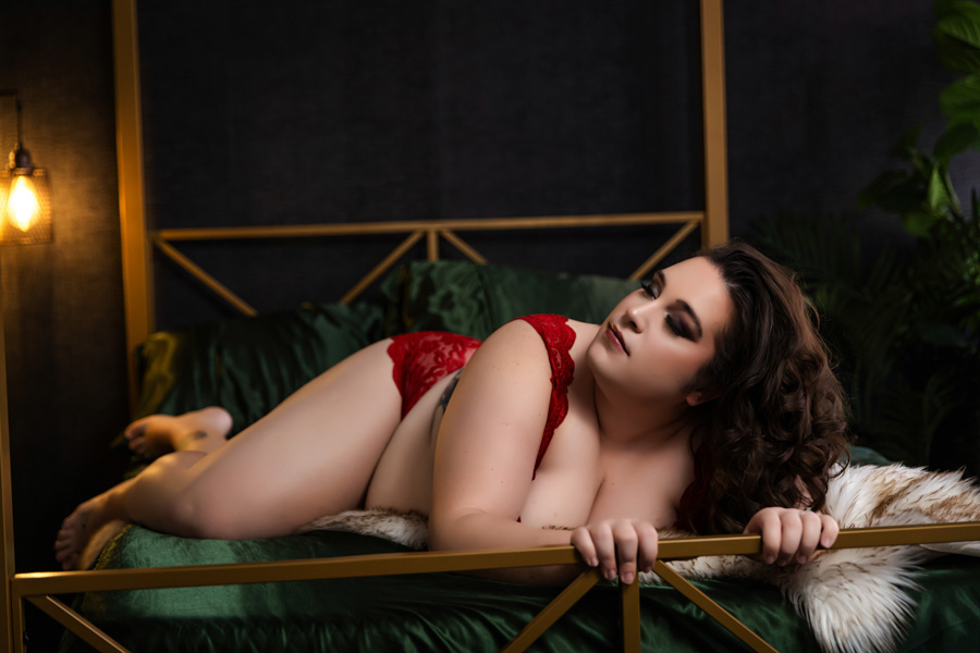 pittsburgh plus size boudoir at pittsburgh's best boudoir studio, woman in red bra and panties posing on gold bed with satin sheets and sheepskin fur