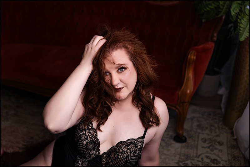 pittsburgh boudoir, self love photo shoot in lingerie posing on red victorian sofa on a designed photo set by Maura Chick